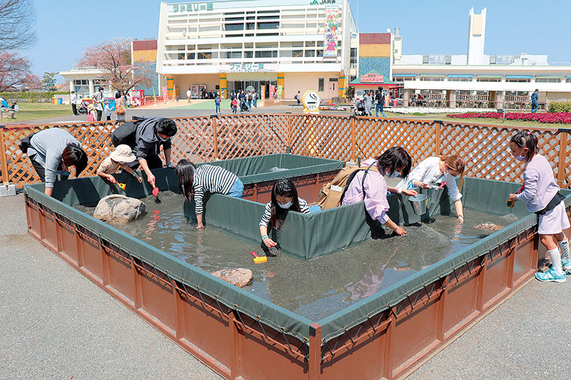 スコップとバケツを持って宝さがしを楽しむ家族連れ＝埼玉県加須市、むさしの村