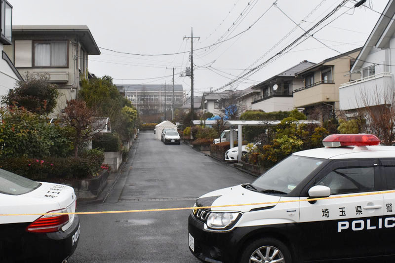 ブルーシートで覆われた被害者宅。一帯は今も規制線が張られ、警察車両も止まっている＝16日午前、飯能市美杉台