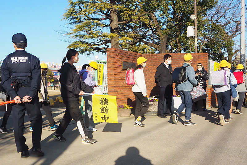 集団下校する並木小学校の児童を見守る警察官ら＝17日午後3時半ごろ、川口市並木