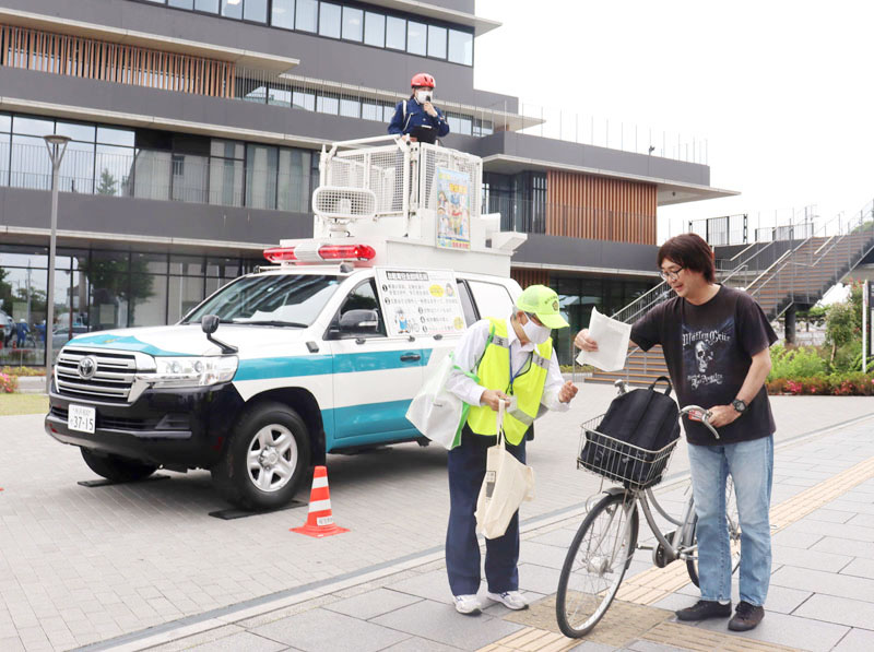 自転車の安全利用を呼びかけるボランティアら。後ろは指揮官車＝5月30日午前、越谷市越ケ谷4丁目