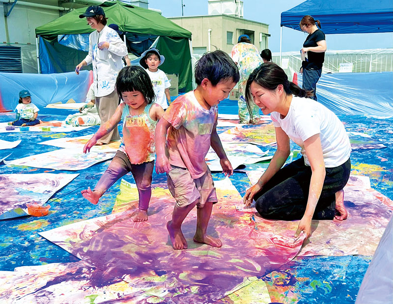 7色の絵の具を使って思い切り遊ぶ子どもたち（中央）＝5月27日、埼玉県さいたま市大宮区高鼻町2丁目のビブリ