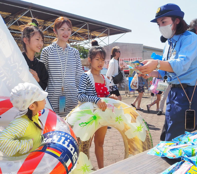 川越水上公園の来場者に啓発品を手渡す埼玉県警職員＝24日午前、川越市