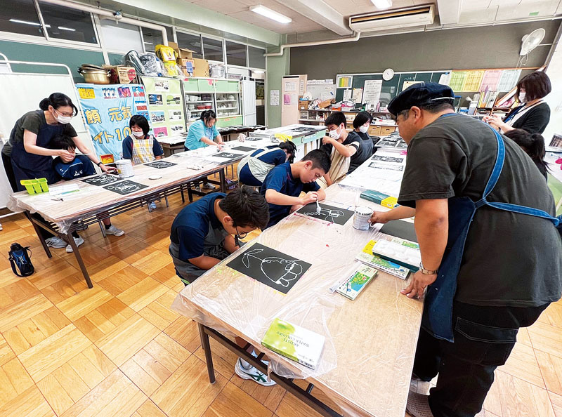 椎名直行さん（右）の指導を受けながら、ペンキとスプーンで絵を描く生徒ら＝26日、埼玉県さいたま市北区の市立植竹中学校