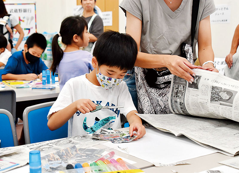 オリジナル新聞を製作する親子＝7月30日午前11時10分ごろ、さいたま市北区の埼玉新聞社