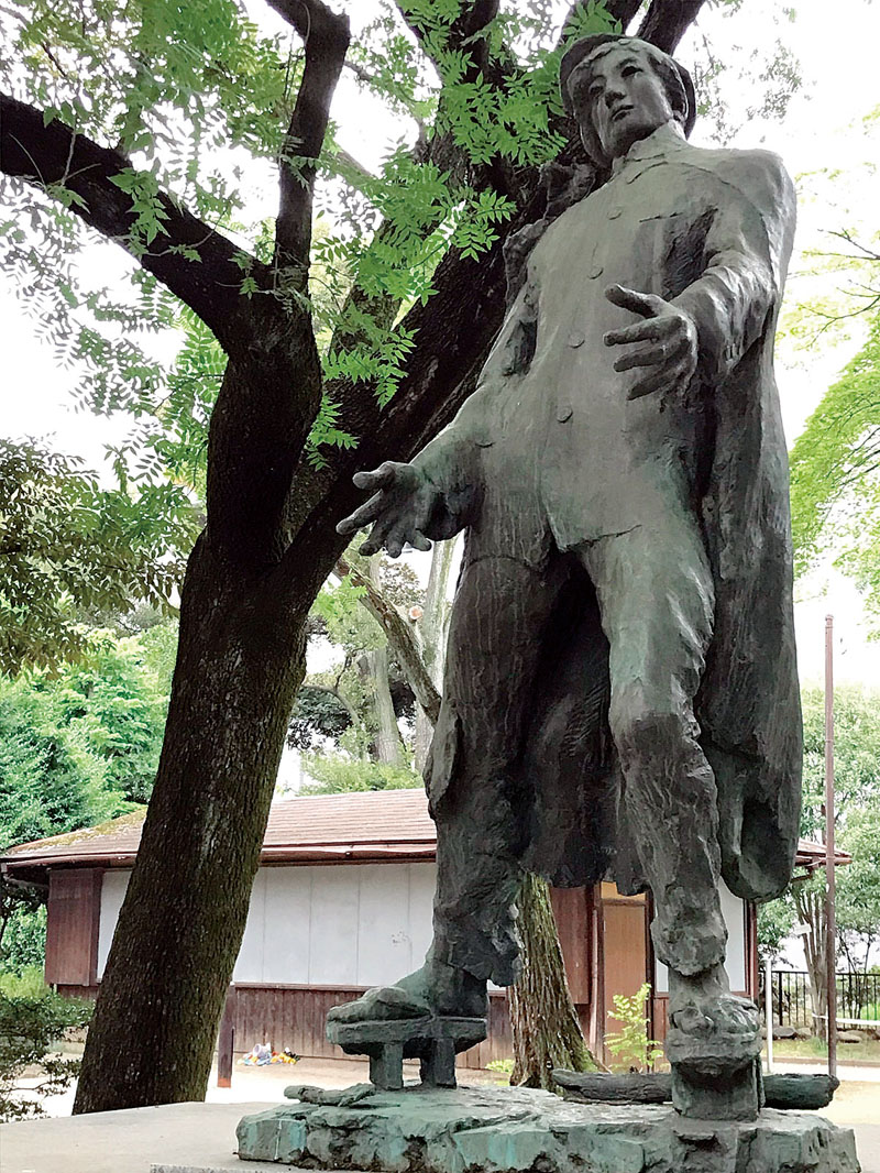 旧制浦和高等学校の跡地を伝えるバンカラ像とカイノキ。大正時代から見守り続ける
