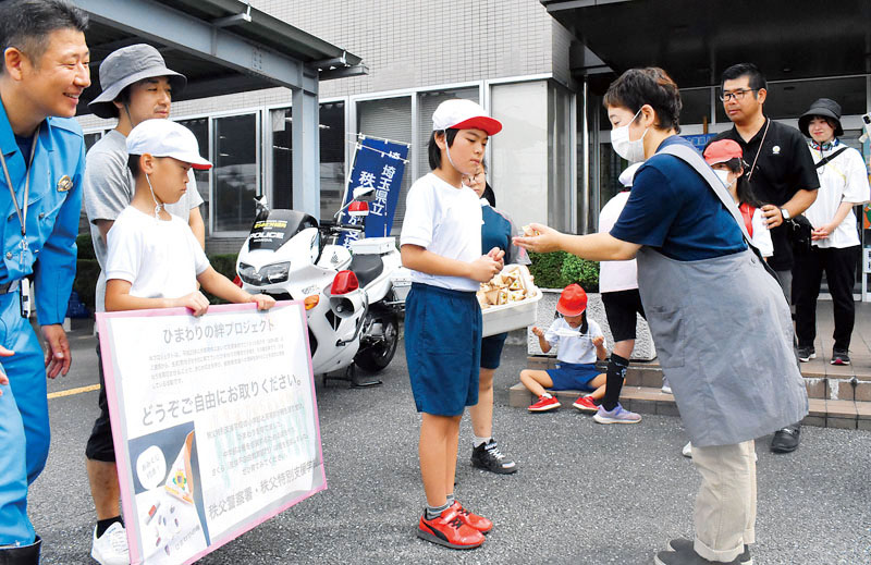 来署者にヒマワリの種を手渡す秩父特別支援学校の児童＝20日午前、秩父署