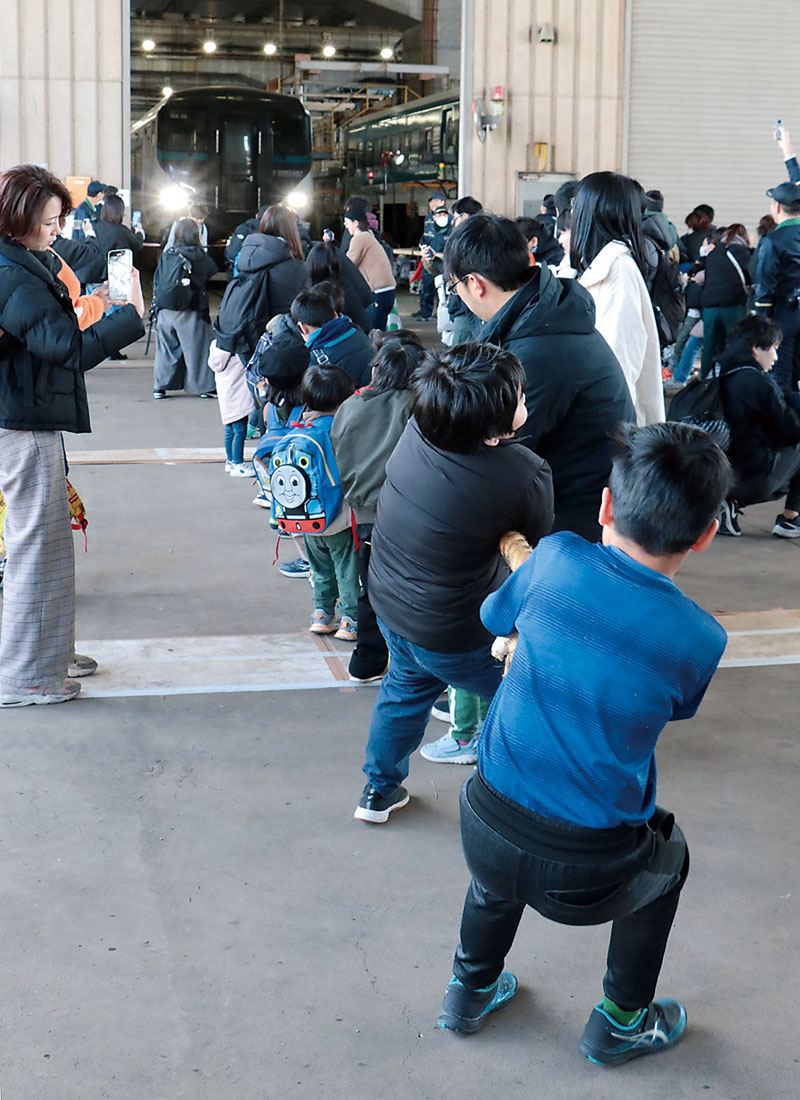 電車と綱引きする親子ら＝25日、埼玉県さいたま市大宮区のJR東日本大宮総合車両センター