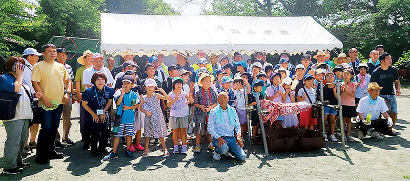 豚肉の塊を前に記念撮影する児童と卒業生、地域住民、学校関係者ら＝7日、熊谷市妻沼台の市立男沼小学校校庭
