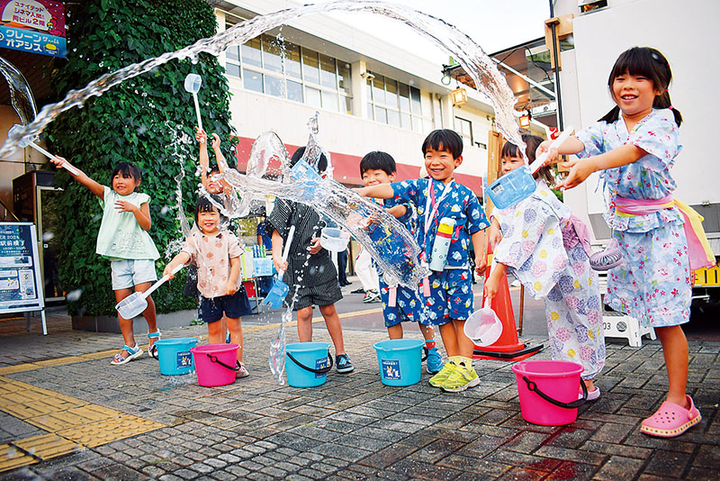 暑さの中、打ち水を楽しむ子どもたち＝1日、入間市駅前