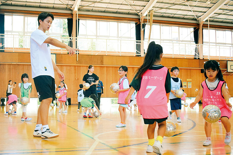 児童にボールの扱い方を教える福西崇史さん（左）＝狭山市北入曽