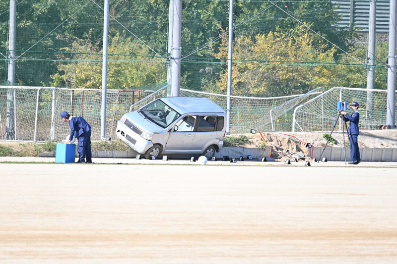 乗り上げた軽乗用車を捜査員が調べる＝17日午後0時40分ごろ、さいたま市西区