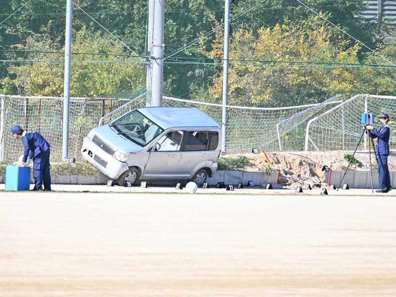 乗り上げた軽乗用車を捜査員が調べる＝17日午後0時40分ごろ、さいたま市西区