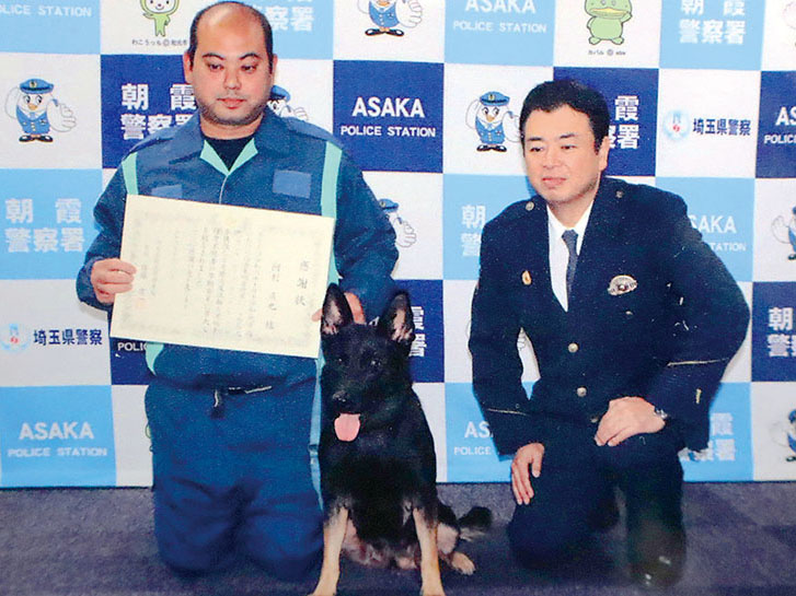 佐藤庸一署長（右）から感謝状を授与された阿利直也さん。中央は警察犬のユッカ＝朝霞署（同署提供）