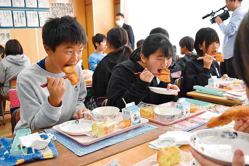 ファミチキを頬張る児童ら＝20日、狭山市鵜ノ木