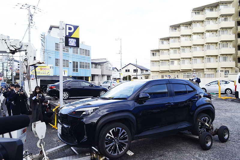 現場に隣接した駐車場から運び出される車両＝27日午後2時ごろ、所沢市東住吉