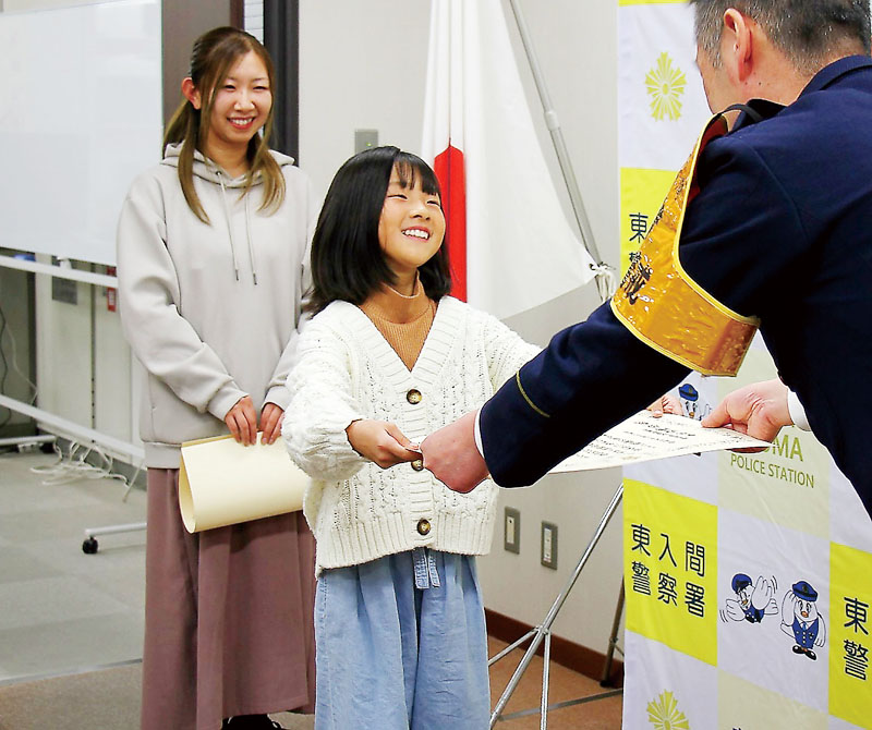 東入間署の西嶋俊哉署長（右）から感謝状を受け取った西田芽以さん（中央）と母の明日香さん＝25日、東入間署