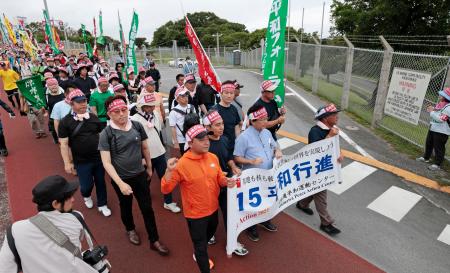 　米軍普天間飛行場のゲート前を通る「平和行進」の参加者＝１８日午前、沖縄県宜野湾市