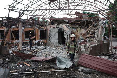 　２２日、ウクライナ東部ハリコフで、ロシア軍の攻撃を受けた現場を調べる救急隊員ら（ゲッティ＝共同）