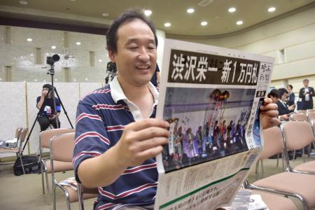 埼玉新聞の号外を手にする男性＝３日午後、さいたま市浦和区