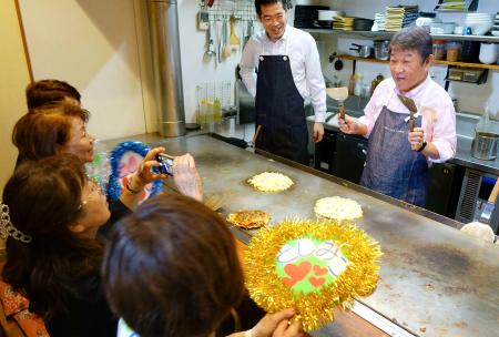 　鉄板焼き屋を貸し切って開いた女性との対話集会で、関西風のお好み焼きを振る舞う自民党の茂木幹事長（右端）＝６日午後、広島県東広島市