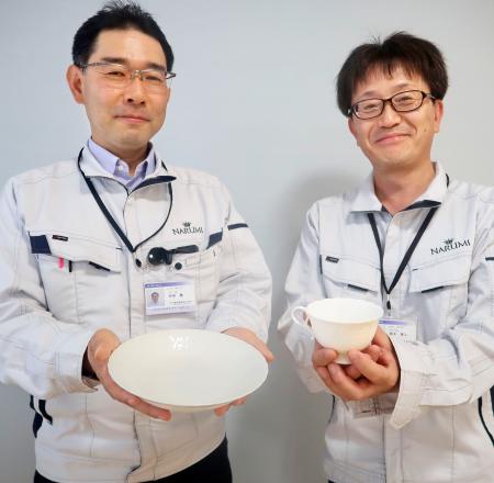 廃棄される卵の殻を使った高級食器「ボーンチャイナ」を手にする鳴海製陶研究開発部の西部徹部長（左）ら＝５月、名古屋市