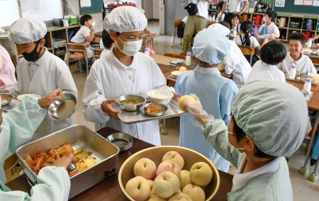 給食に提供された桃を配る児童＝１１日午後、岡山市の市立加茂小