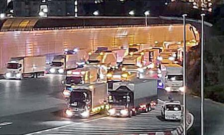 東名高速道路の東京料金所前で、深夜割引が適用される午前０時を待つため滞留するトラック＝２０２０年１２月、川崎市（中日本高速道路提供）