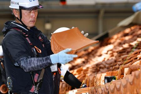 　再建中の首里城正殿で、赤瓦で屋根をふく作業を行う職人＝１５日午後、那覇市