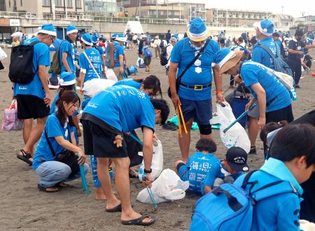 片瀬東浜海水浴場で青色のサンタ姿で清掃活動をするイベントの参加者＝１５日午後、神奈川県藤沢市