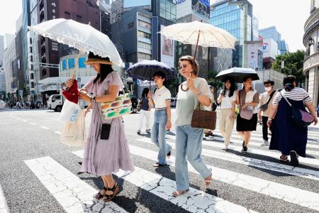 日傘を差し、東京・銀座を歩く人たち＝２２日午後