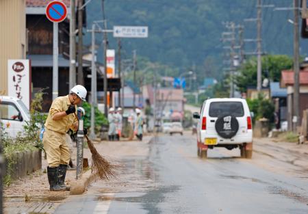 浸水した山形県戸沢村の古口地区で国道４７号を掃除する人＝２７日午前９時２５分