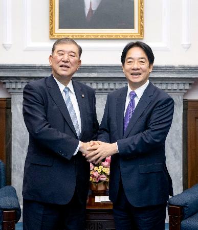 台湾総統府で、頼清徳総統（右）と握手する自民党の石破元幹事長＝１３日午前（総統府提供・共同）