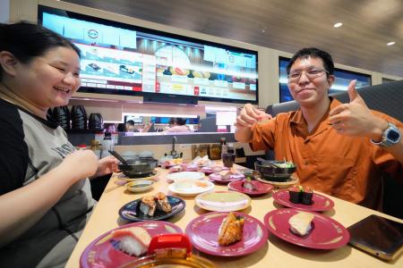 　開業した「スシロー」の北京市での第１号店ですしを食べる人たち＝２１日（共同）