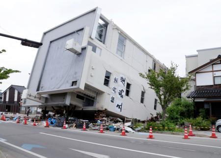 能登半島地震で倒壊し、横倒しのままとなっている石川県輪島市の７階建てビル＝２２日午後