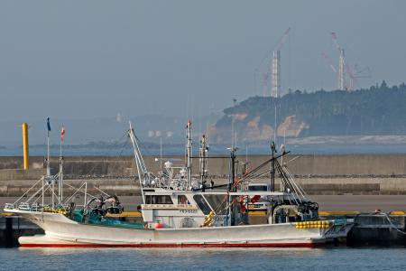 福島県浪江町の請戸漁港に停泊する漁船。奥は東京電力福島第１原発の排気筒＝２４日午前