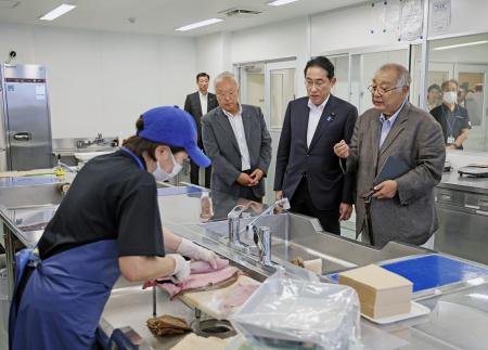 福島県いわき市の小名浜魚市場で魚の下処理の様子を視察する岸田首相。右端は福島県漁連の野崎哲会長＝２４日午後（代表撮影）