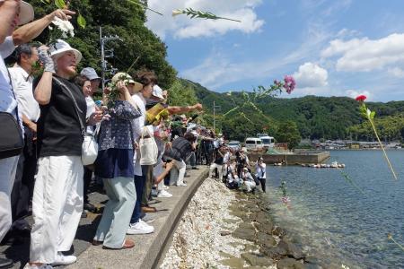 浮島丸が沈んだ海に花を投げ入れる追悼集会の参加者たち＝２４日、京都府舞鶴市