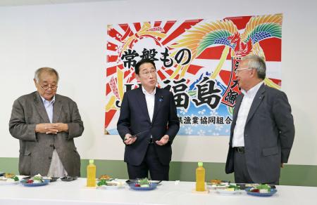 　食堂で海産物などを試食する岸田首相。左は福島県漁連の野崎哲会長＝２４日午後、福島県いわき市の小名浜魚市場（代表撮影）