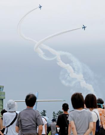 航空自衛隊松島基地の航空祭で、アクロバット飛行を披露する「ブルーインパルス」と訪れた観客＝２５日午後、宮城県東松島市