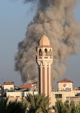 ２５日、ガザ中部デールバラハで、イスラエル軍の攻撃を受けて住宅街から上がる煙（ゲッティ＝共同）