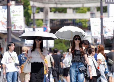 猛暑日が続く福岡県太宰府市で日傘を差して歩く人たち＝２３日