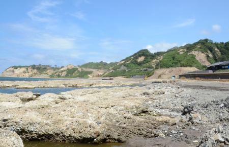 能登半島地震で隆起した石川県輪島市の海岸。奥は大規模な土砂崩落現場＝８月