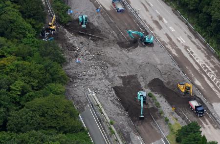 重機を使った撤去作業が続く、大分自動車道由布岳パーキングエリア付近の土砂崩れ現場＝１日午前１１時２９分、大分県由布市（共同通信社ヘリから）