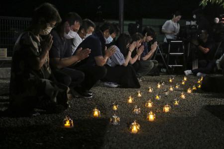 紀伊半島豪雨から１３年となった和歌山県那智勝浦町で、キャンドル形ＬＥＤの明かりに手を合わせ犠牲者をしのぶ人たち＝４日未明