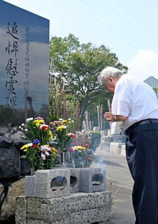 福田村事件から１０１年となり、慰霊碑に向かい手を合わせる人＝６日午前、千葉県野田市