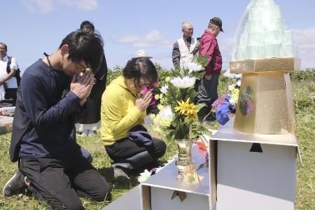 北方領土・択捉島のペケンリタ墓地での慰霊式で手を合わせる墓参団員＝２０１９年７月