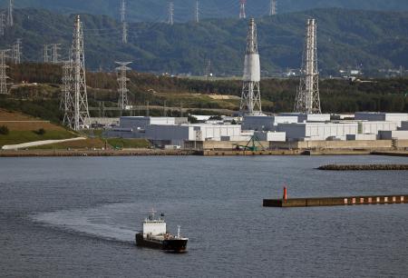 新潟県の東京電力柏崎刈羽原発（奥）を出港する、使用済み燃料を運搬する専用船＝２４日午後４時２３分（共同通信社ヘリから）