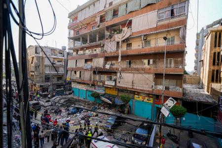 ２４日、レバノン・ベイルート南部の郊外でイスラエル軍の空爆を受けた建物を確認する住民と救助隊（ＡＰ＝共同）