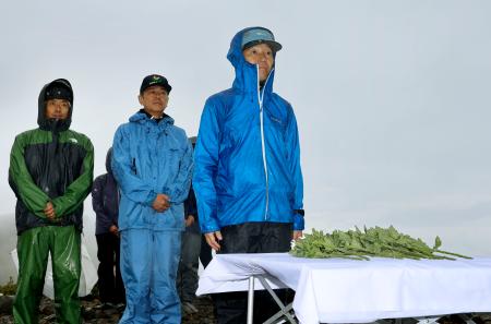 御嶽山の噴火から１０年となり、活動拠点となった９合目で噴火口に向かい献花する青木幹典さん（右）＝２７日午前、岐阜県下呂市