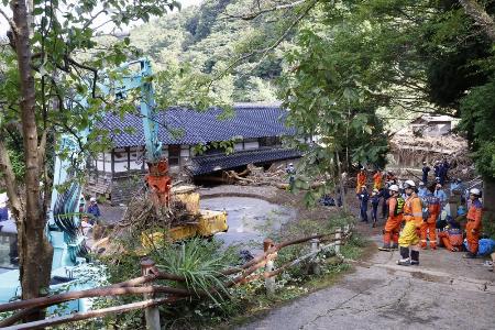 石川県能登町の北河内地区で、がれきの撤去作業を見守る消防隊員ら＝２５日